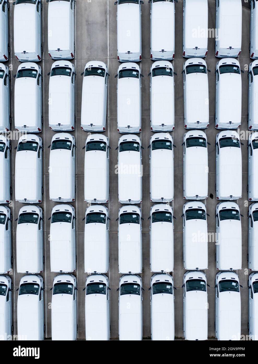 Eine Luftaufnahme von Reihen neuer weißer Lieferwagen, die frisch von der Produktionslinie in der Fabrik eines Automobilherstellers stammen Stockfoto