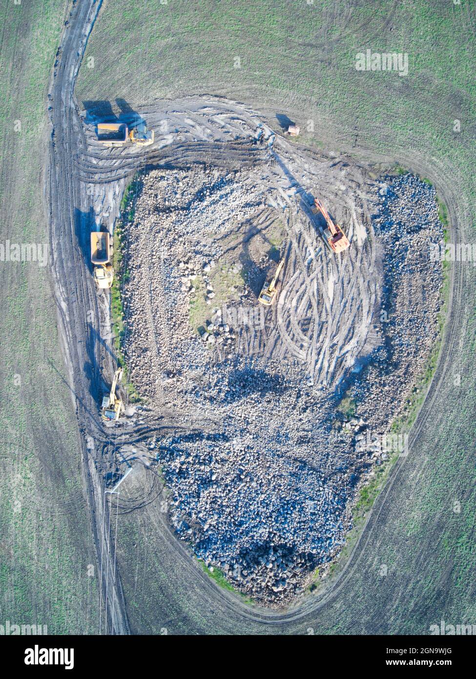 Baustellen-Luftaufnahme mit schweren Geräten, Erdbewegern, Muldenkipper, die an Bodenaushub in einem grünen Feld arbeiten, Victoria, Australien. Stockfoto