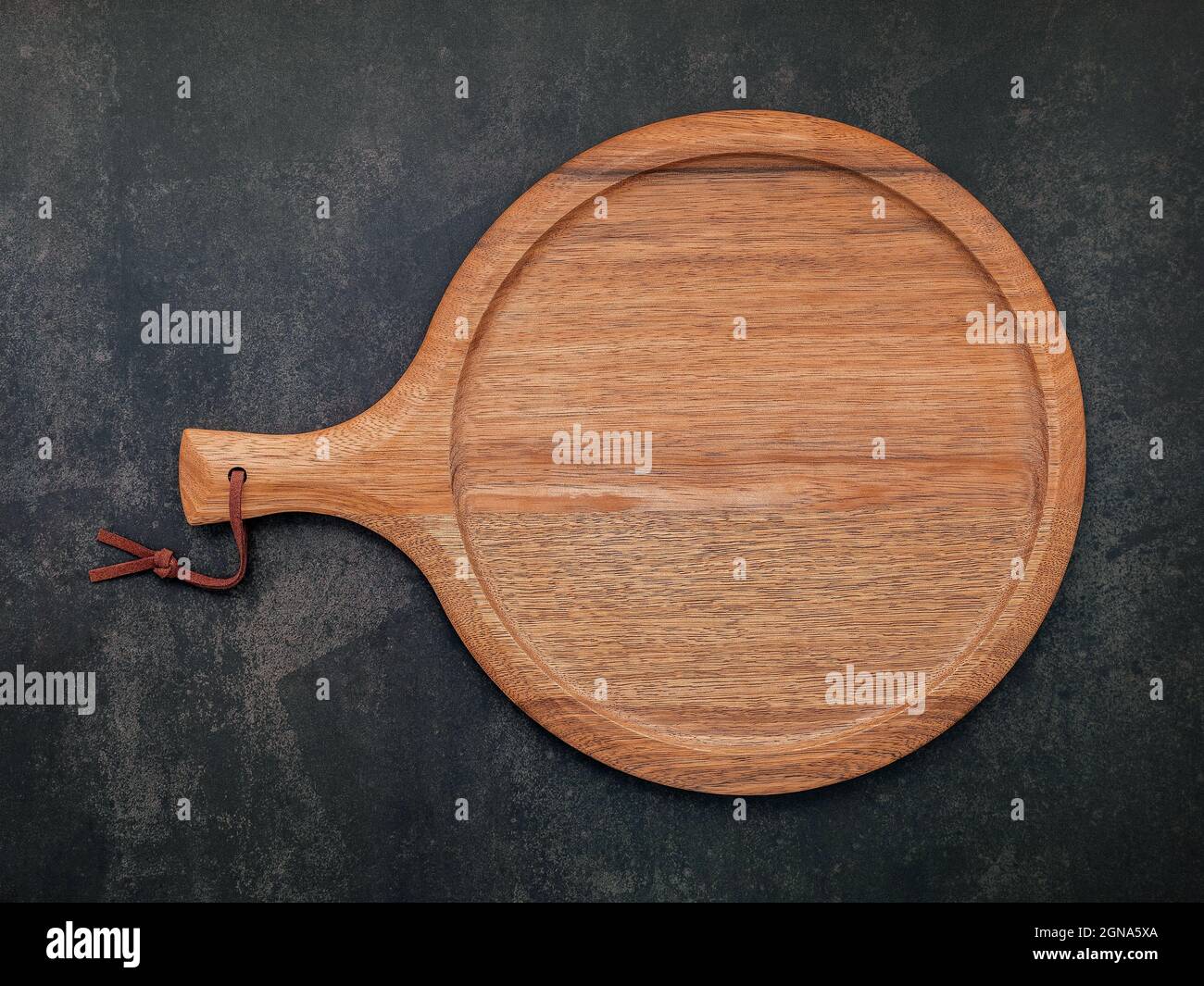 Leere hölzerne Pizzaplatte auf dunklem Beton aufgestellt. Pizza Tablett auf dunklem Beton Hintergrund flach legen und kopieren Platz. Stockfoto