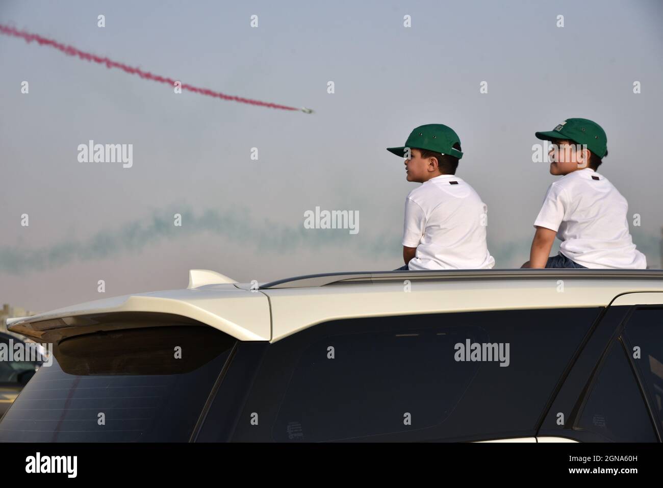 Riad, Saudi-Arabien. September 2021. Zwei Kinder sitzen auf dem Dach eines Autos, um sich die Airshow im um Ajlan Park in Riad, Saudi-Arabien, anzusehen, 23. September 2021. Die Airshow fand hier am Mittwoch und Donnerstag statt, um den Nationalfeiertag des Landes zu feiern. Kredit: Hu Guan/Xinhua/Alamy Live Nachrichten Stockfoto
