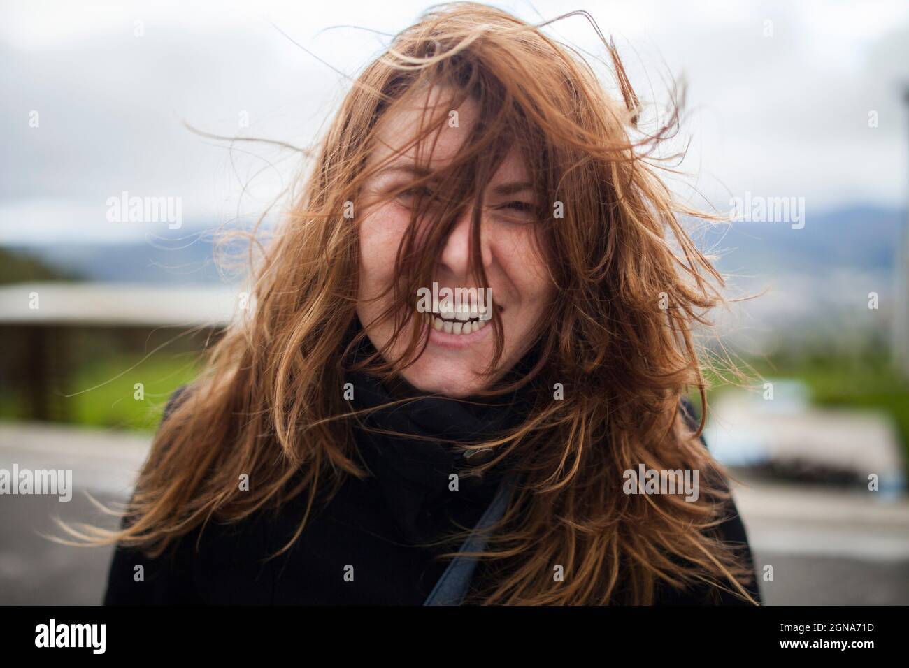 Schönes Mädchen lächelnd chaotisch Haar Fokus Touren Tiefe des Feldes windigen Berge glücklich Stockfoto