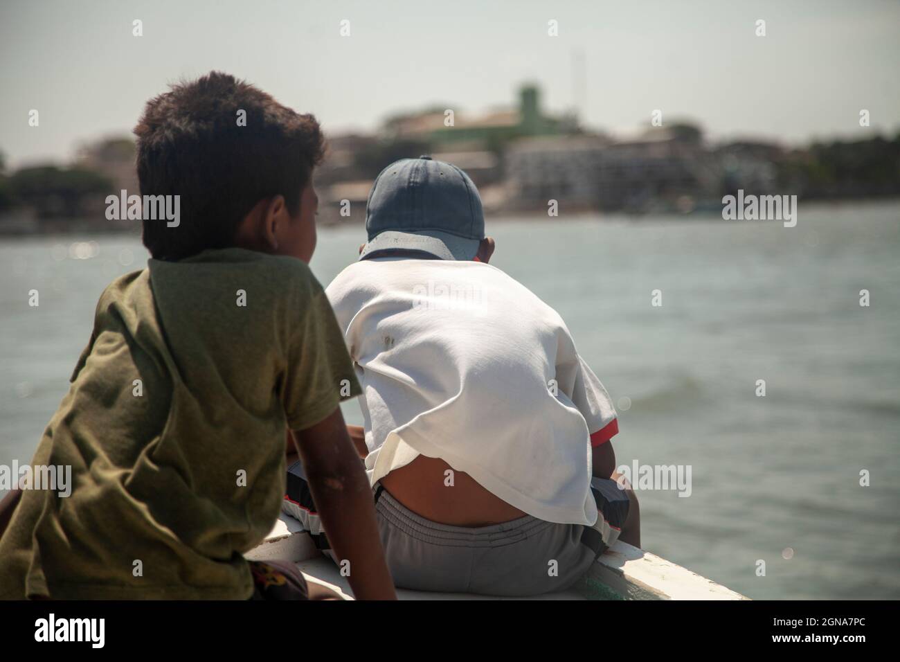 Zwei arme Kinder, die vor einem Fischerboot fahren Armut im Land der Dritten Welt Stockfoto