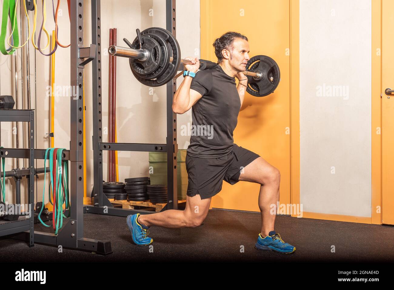 Mann macht Kniebeugen mit Bar im Fitnessstudio Stockfoto