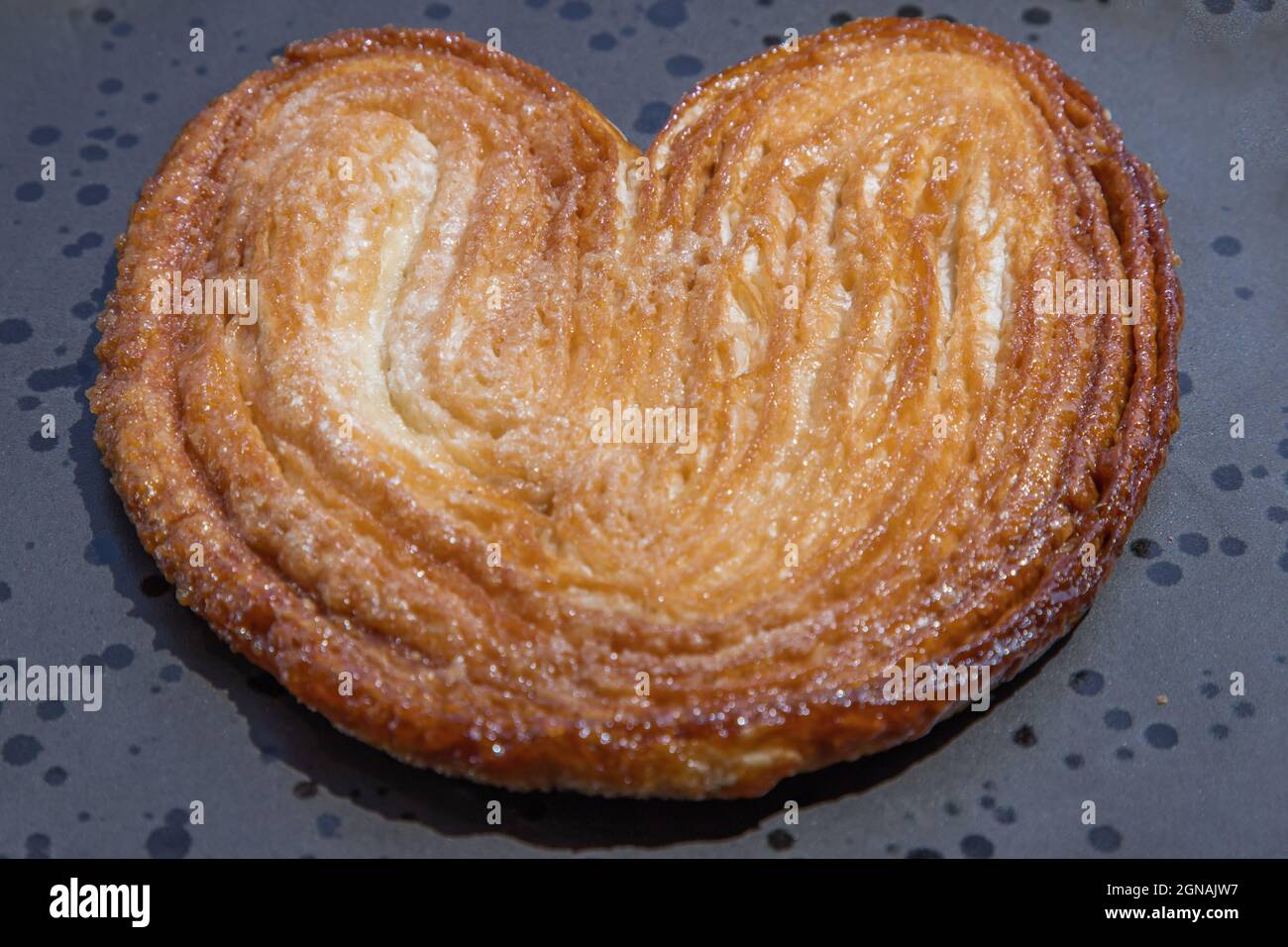 Nahaufnahme von Butterpalmenbrot, franzsischem Gebck in Palmblatt oder  einer Schmetterlingsform sehen manchmal aus wie Schwein- oder Elefantenohr  auf schwarzem Teller. Selecti Stockfotografie - Alamy