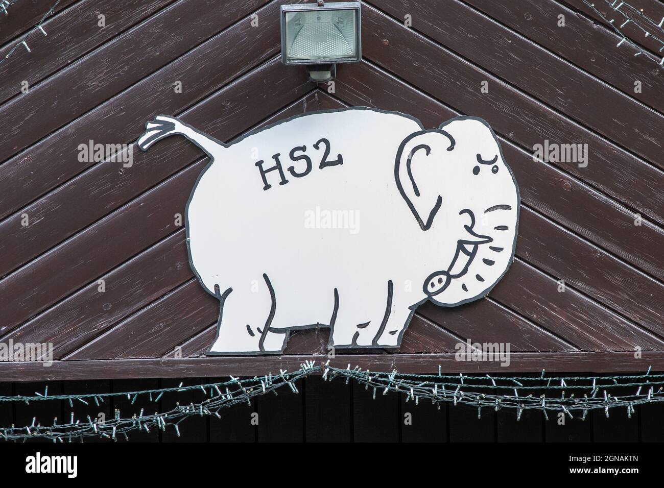 Ein Schild über einer Garage in Red Lane Burton Green deutet darauf hin, dass die nahe gelegene HS2-Eisenbahnkonstruktion ein weißer Elefant ist. Stockfoto