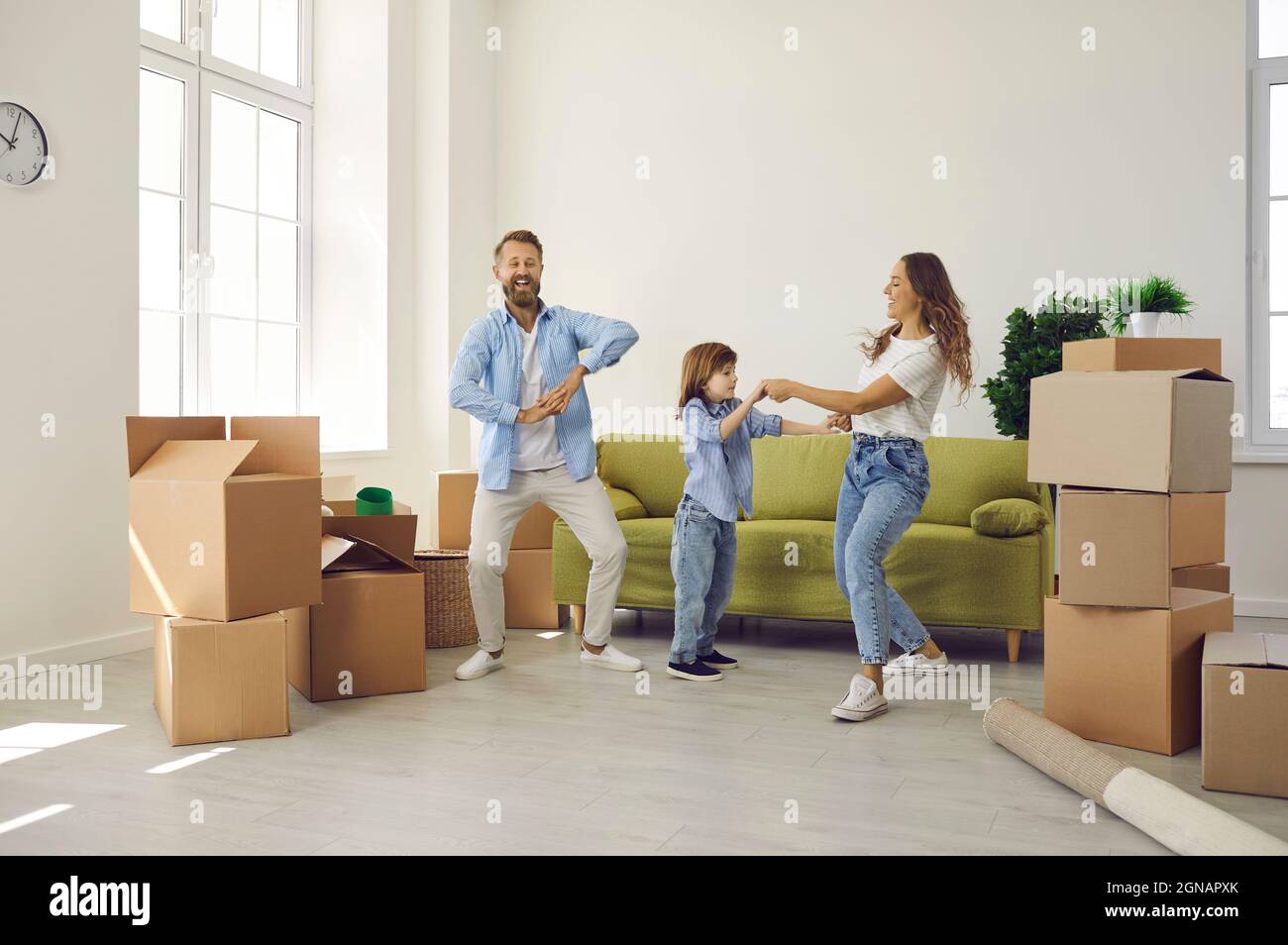 Glückliche Mutter, Vater und Kind tanzen und Spaß haben in ihrem neuen Haus am Umzugstag Stockfoto