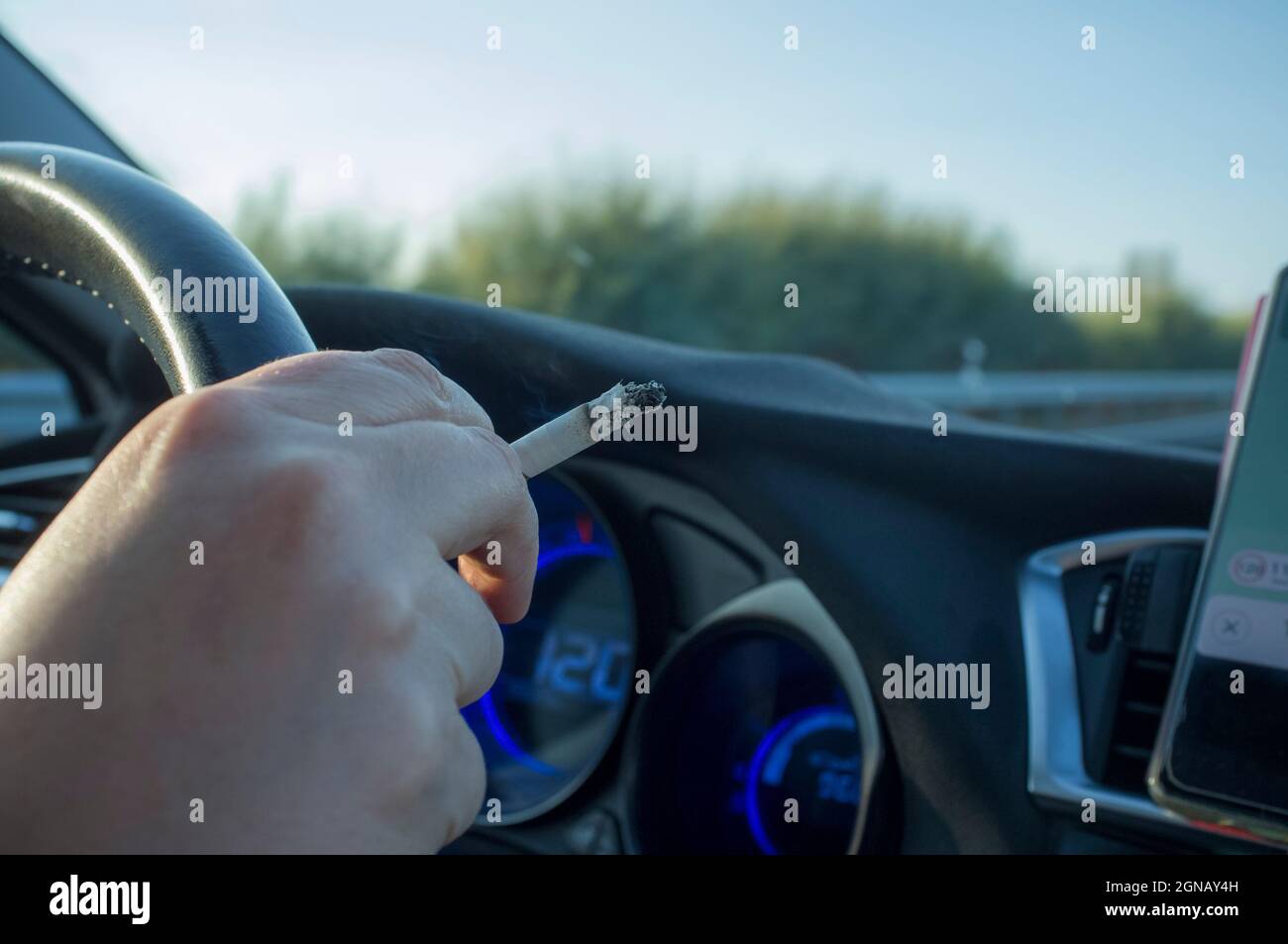 Frau raucht, während sie fährt. Konzept für die Ursache von abgelenkten Fahrunfällen. Innenansicht des Fahrzeugs Stockfoto