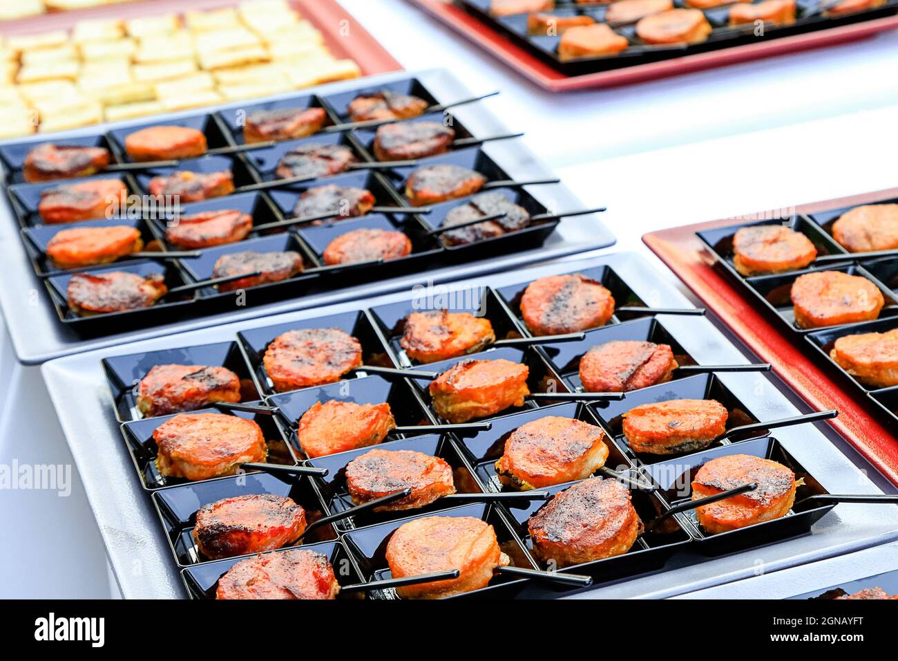 Catering Fingerfood aus der Nähe. Kleine orientalische Snacks auf quadratischen schwarzen Tellern mit winzigen Löffeln. Gourmetküche. Menü-Konzept-Bild Stockfoto