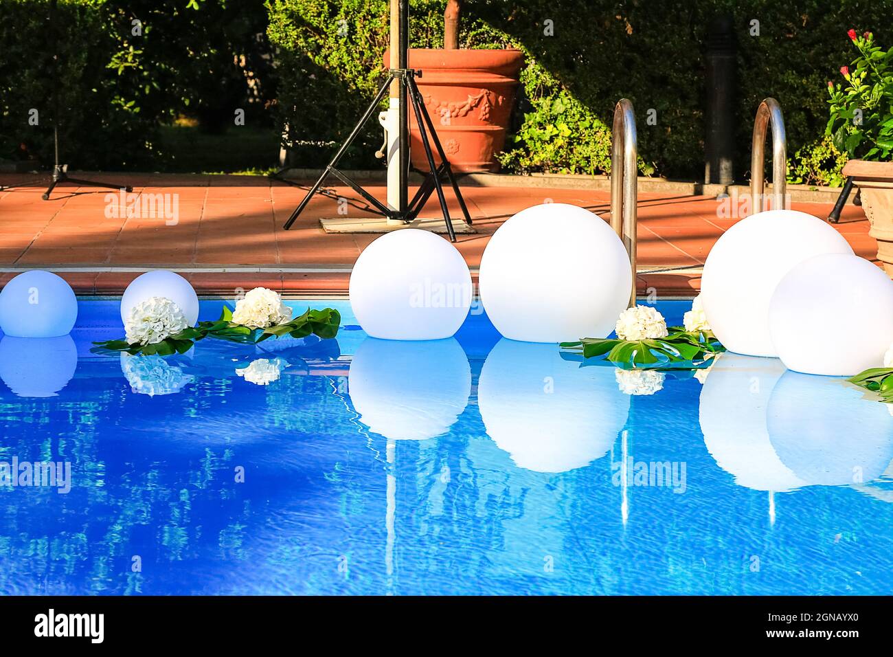 Open-Air-Swimmingpool, dekoriert mit weißen schwimmenden Kugeln und frischen Blumen für Hochzeitsfeiern. Vorbereitung der Sommerveranstaltung. Party-Design. Sauber Stockfoto