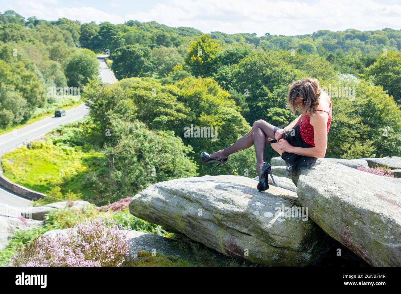 Derbyshire UK – 20. Aug 2020: Simon fixiert seine Strümpfe auf dem Krötenmund, einer ikonischen Felsformation mit Blick auf die A6187 Hathersage Road, Peak District Stockfoto