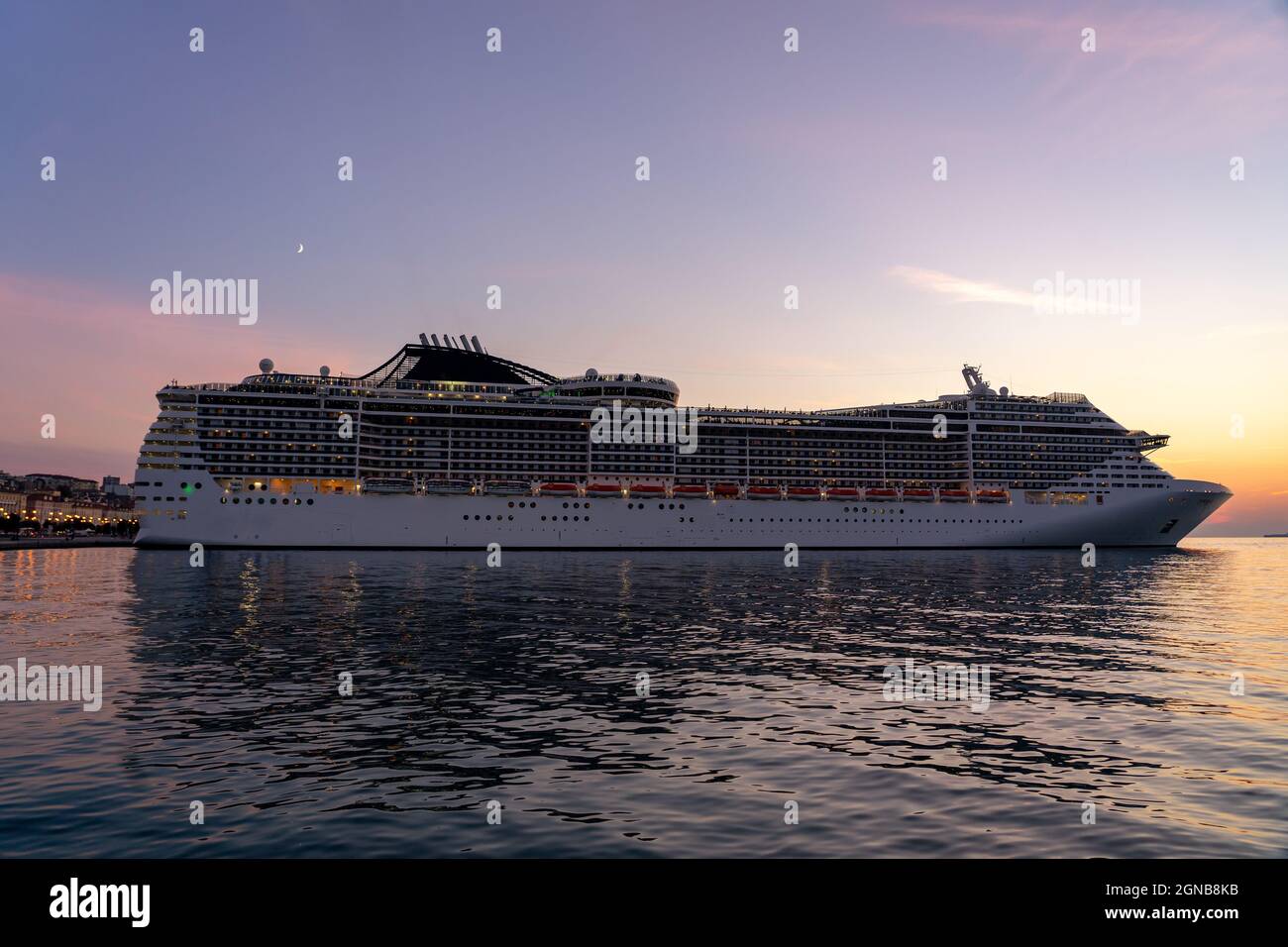 Riesiges Cruiser-Schiff bei Sonnenuntergang mit Lichtern Stockfoto