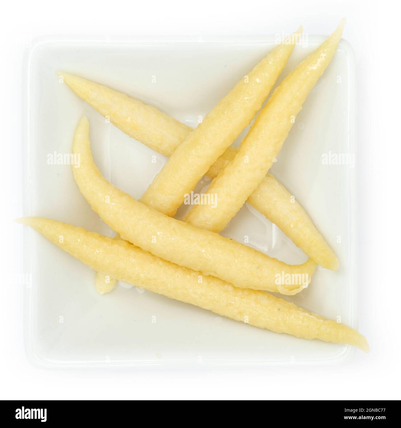 Nahaufnahme schwäbischer Fingernudeln in einer weißen quadratischen Schüssel, isoliert auf weißem Hintergrund Stockfoto