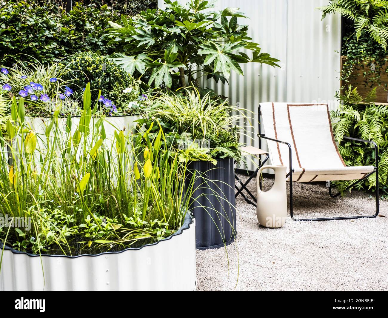 Eine Schotterterrasse mit Stuhl und reich bepflanzten Behältern. Stockfoto