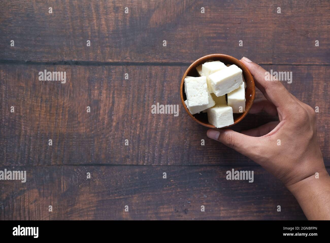 Mann Hand hält eine Schüssel mit Käse auf dem Tisch Stockfoto