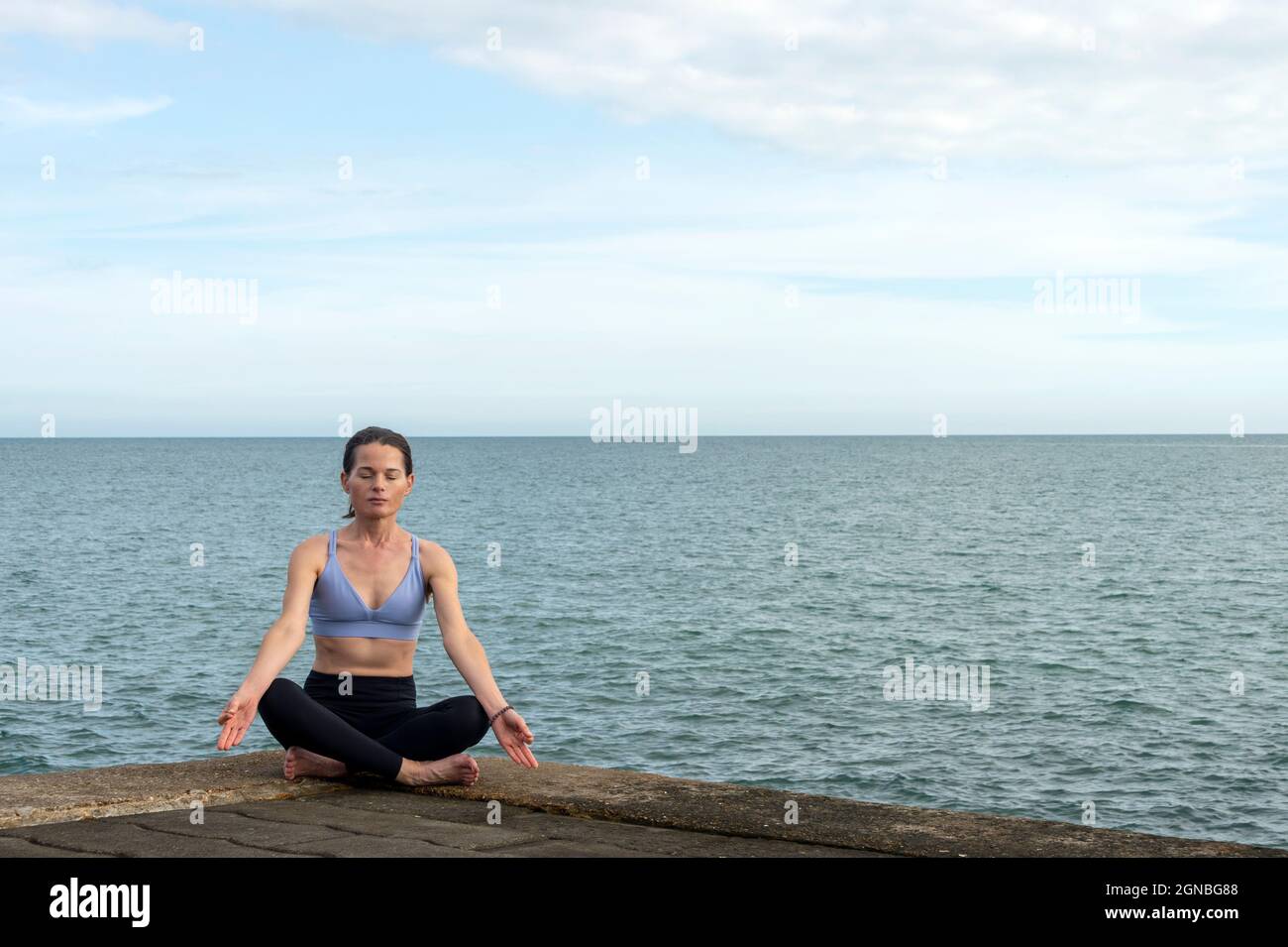 Attraktive Frau meditiert und praktiziert Yoga am Meer. Stockfoto