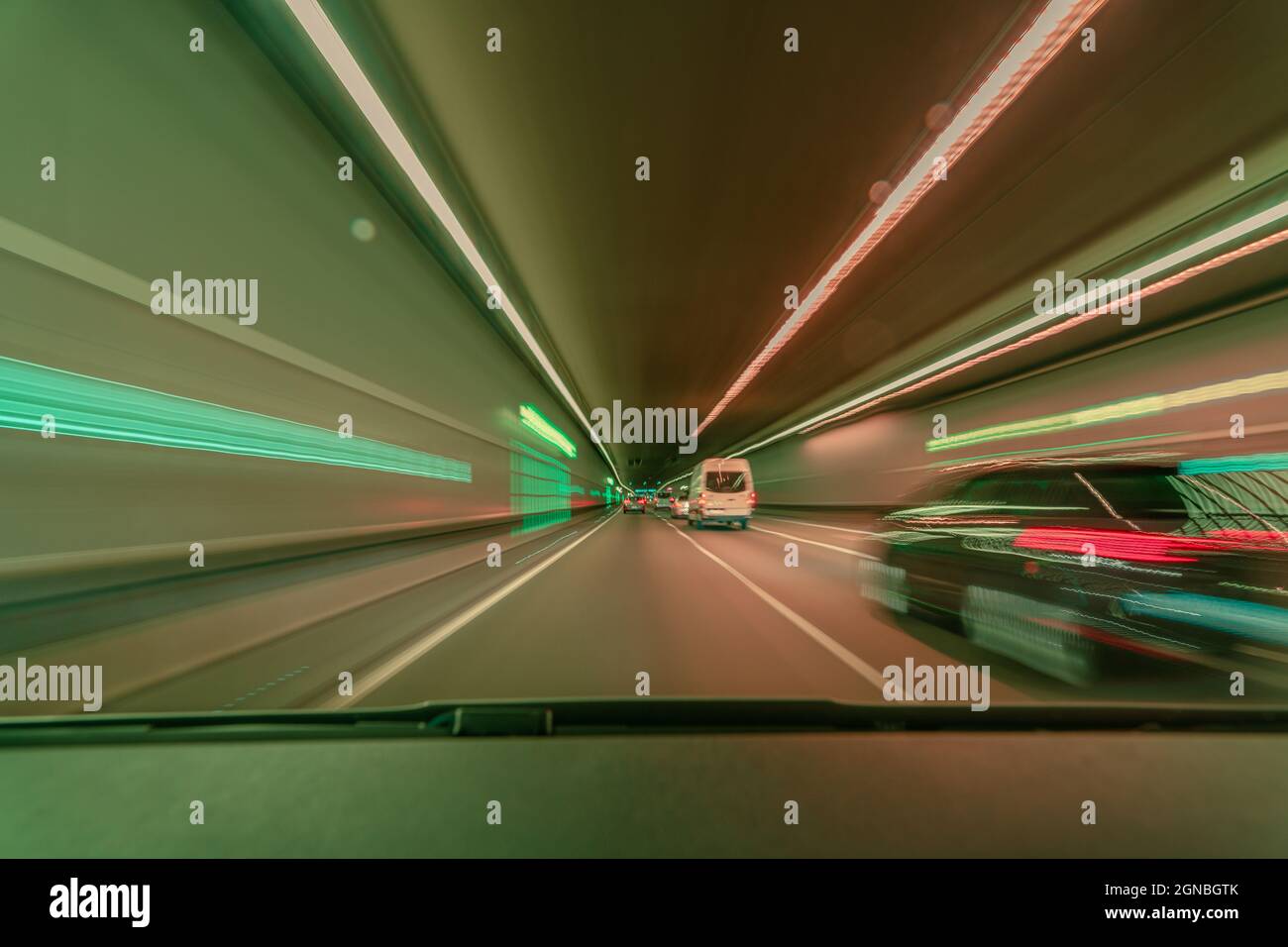 Highspeed verwackelte Hintergrundkulisse, die schnell durch einen Tunnel fährt und ein Auto mit hellen verschwommenen Langzeitbelichtungseffekten überholen Stockfoto