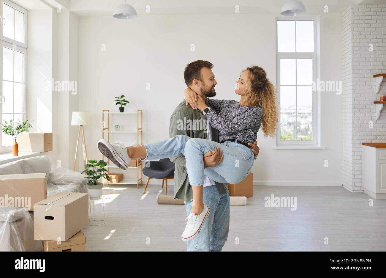 Romantisches Porträt eines fröhlichen und zufriedenen jungen verliebten Paares, das in sein neues Zuhause zieht. Stockfoto