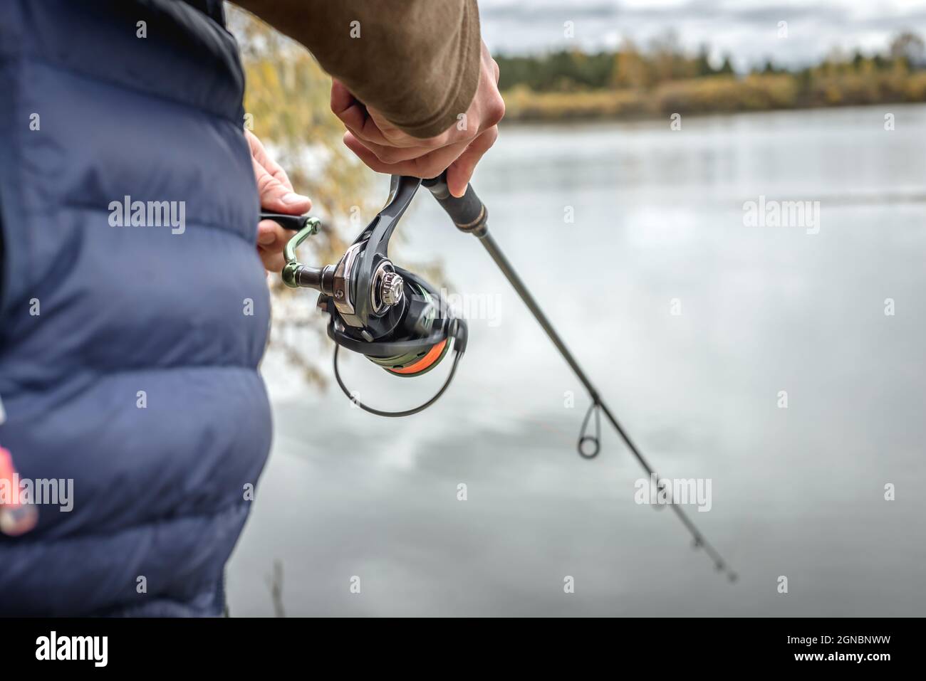 Der männliche Fischer fischt an einem ruhigen Ort am Fluss im Herbstwald. Nahaufnahme. Stockfoto