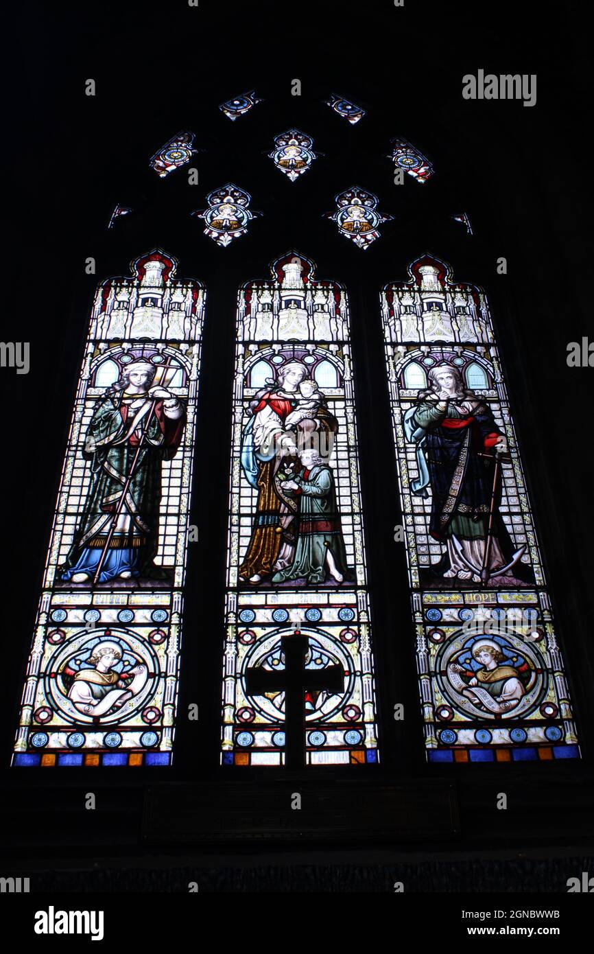 Buntglasfenster von Faith Hope and Charity in der St. Thomas the Martyr Kirche in Up Holland auf schwarzem Hintergrund mit Kopierraum. Stockfoto