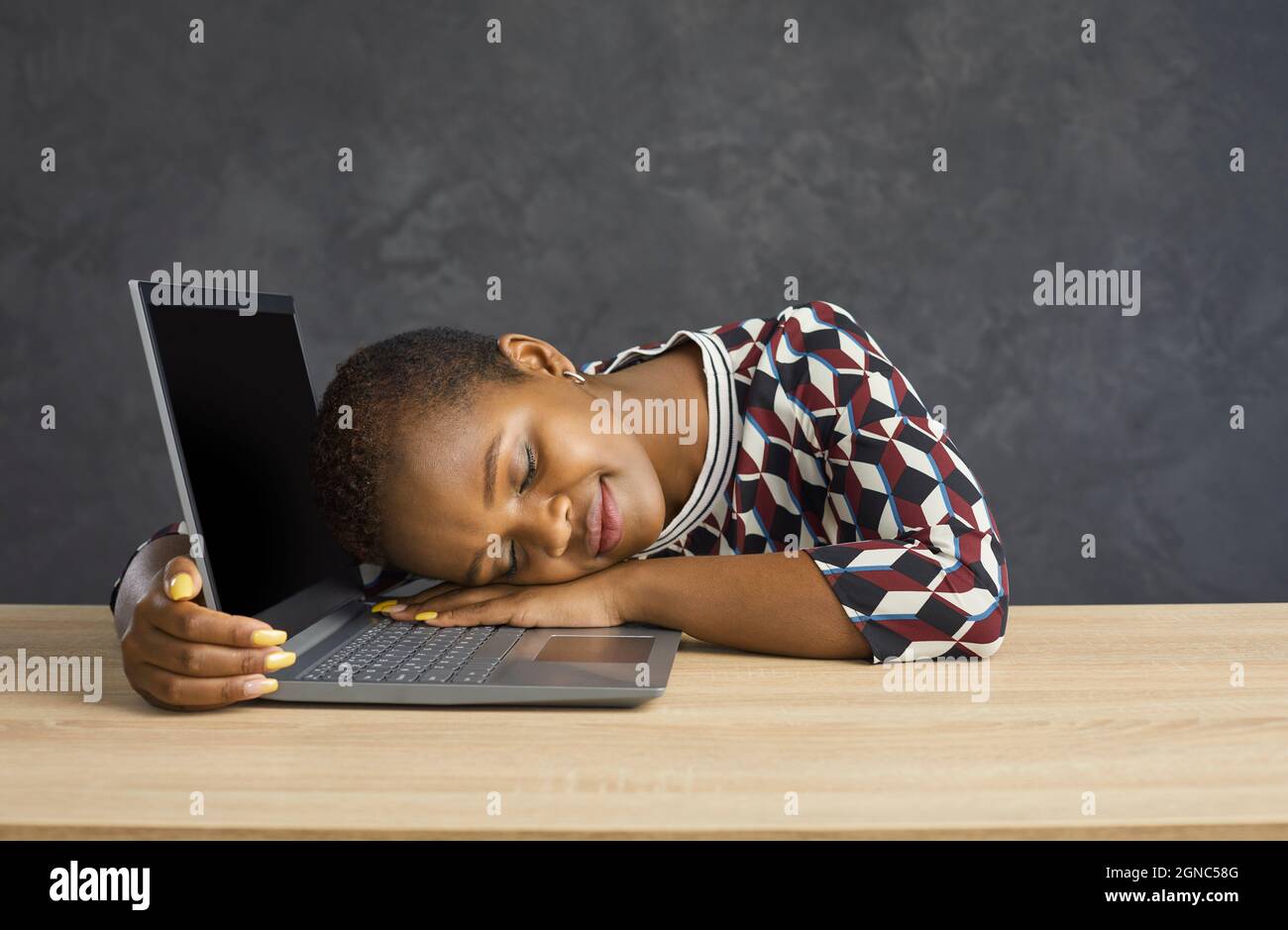 Erschöpfte ethnische Frauen schlafen auf einem Laptop ein Stockfoto