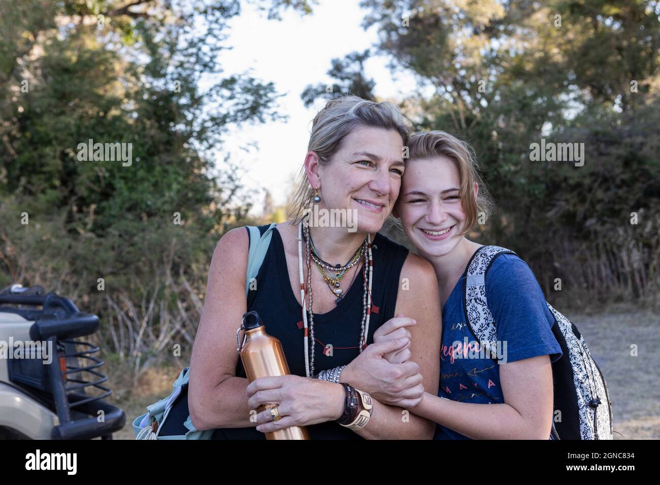 Mutter und Tochter im Teenageralter im Busch auf Safari, Seite an Seite lächelnd, Botswana. Stockfoto