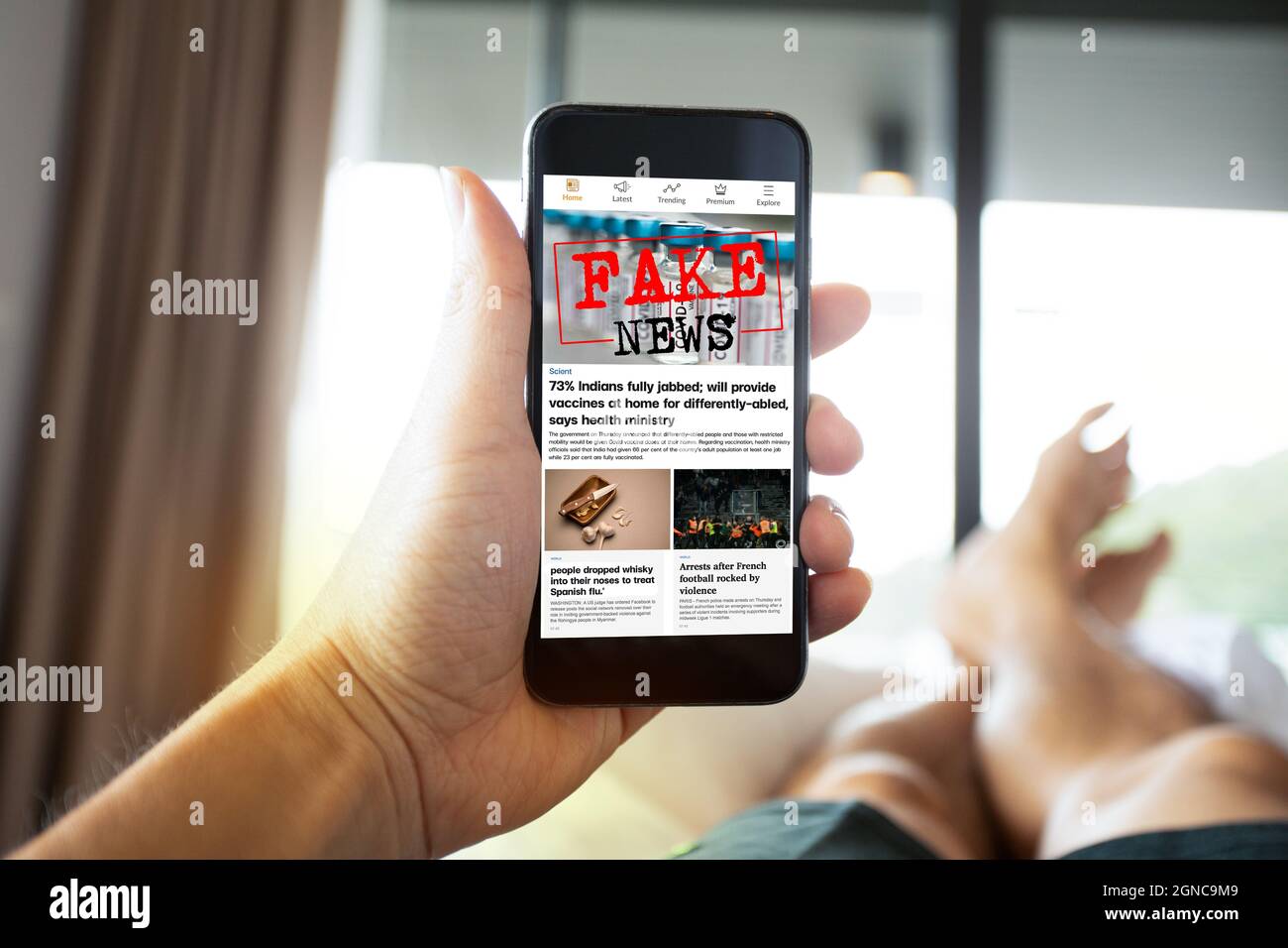 Mann, der gefälschte Nachrichten oder Artikel über covid-19 in einer Smartphone-Bildschirm-Anwendung liest. Mockup-App-Website. Gefälschtes Newsportal. Medientechnik. Stockfoto