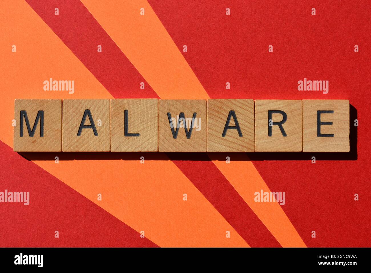 Malware, Wort in Holzbuchstaben isoliert auf rotem und orangefarbenem Hintergrund Stockfoto