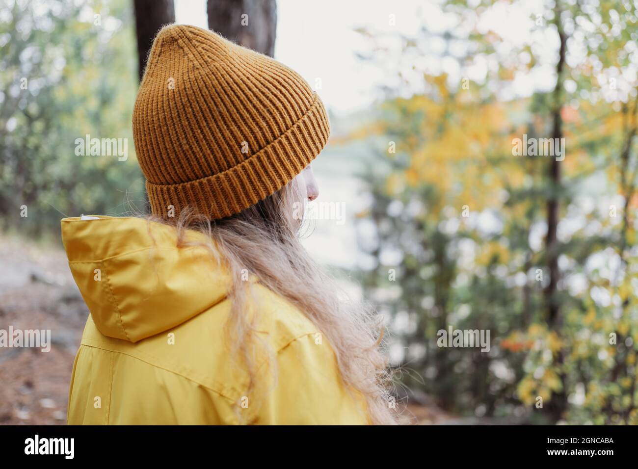 Teenager-Mädchen in gelbem Regenmantel und orange Beanie stehen in einem  Wald und Blick zur Seite. Lokales Reisekonzept. Herbst zu Fuß allein,  Teenager Herbst l Stockfotografie - Alamy