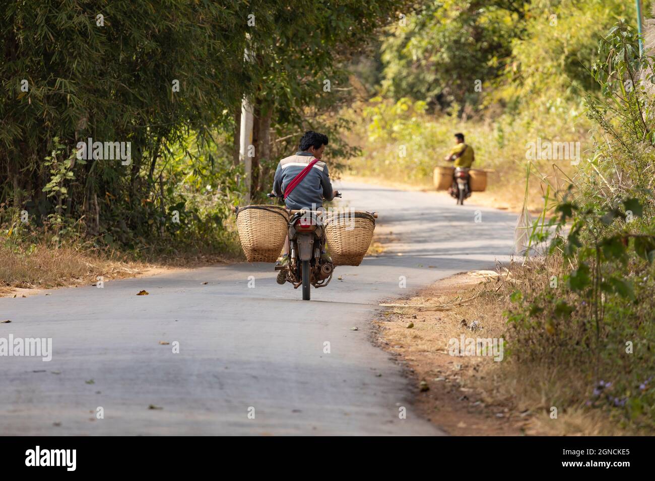 Shan State, Myanmar - 05. Jan 2020: Ein Mann fährt ruhig mit seinem alten Motorrad die West-Korridor-Straße in der Nähe des Inle Lake entlang Stockfoto