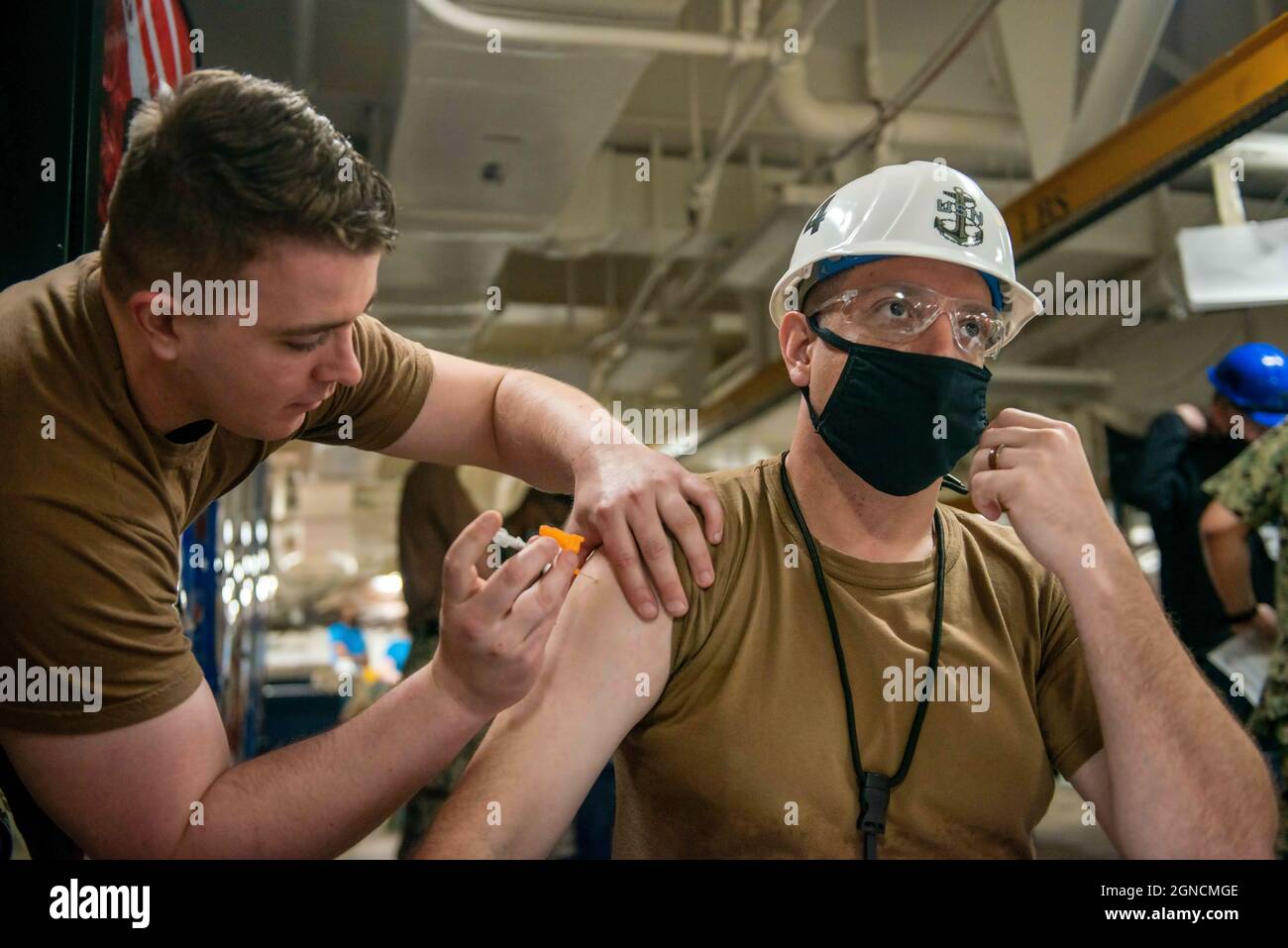 NORFOLK (25. Mai 2021) Chief Aviation Support Equipment Technician Andrew Couillard, rechts, aus Iron Mountain, Michigan, der dem Flugzeugträger USS John C. Stennis (CVN 74) zugewiesen wurde, erhält den COVID-19-Impfstoff vom Hospitalman Henry Mason aus Uhrichsville, Ohio, der dem Flugzeugträger USS George Washington (CVN 73) zugewiesen wurde, In the Mess Decks an Bord von John C. Stennis in Newport News, Virginia, 25. Mai 2021. Die John C. Stennis befindet sich in der Newport News Werft für eine komplexe Betankung als Teil der Mission, das Kriegsschiff im Kampf wieder rechtzeitig und im Rahmen des Budgets zu liefern, um wieder aufzunehmen Stockfoto