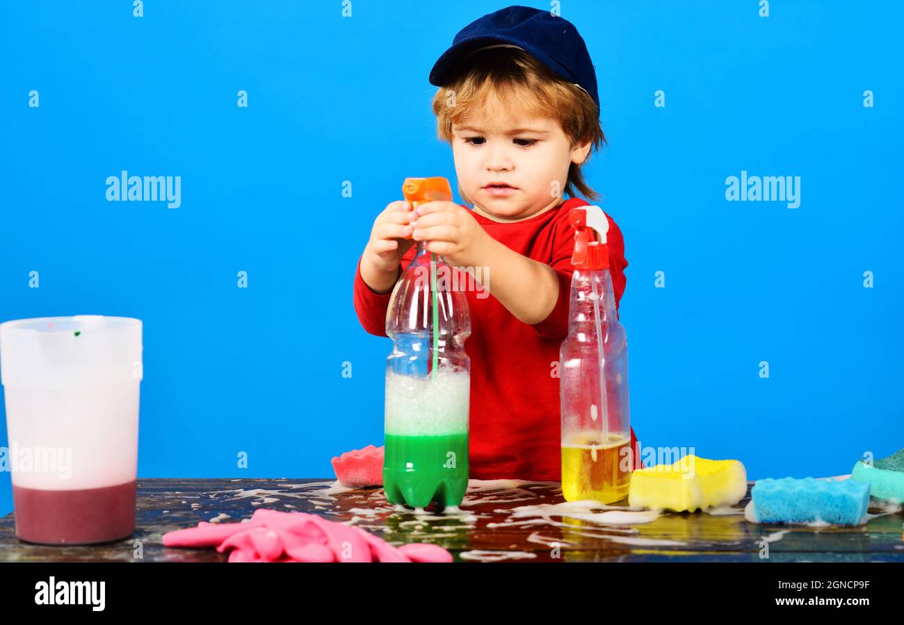 Hausreinigung und Hausaufgaben. Kleiner Junge, der mit Reinigungsspray spielt. Reinigungszubehör Stockfoto