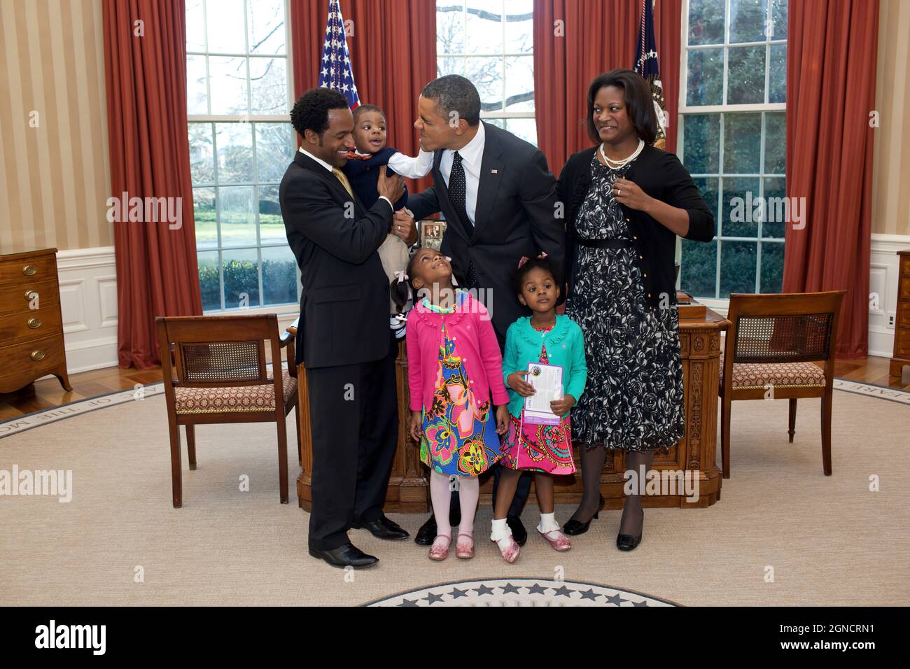 Lauren Fleming, der 2011. März der nationalen Botschafterin von Dimes, schaut auf, während ihr Bruder Corbin Präsident Barack Obamas Gesicht während eines Besuchs im Oval Office am 7. Februar 2012 berührt. Lauren wird auch von ihren Eltern Densel und Nikki Fleming und ihrer Schwester Erin begleitet. (Offizielles Foto des Weißen Hauses von Pete Souza) Dieses offizielle Foto des Weißen Hauses wird nur zur Veröffentlichung durch Nachrichtenorganisationen und/oder zum persönlichen Druck durch die Betreffzeile(en) des Fotos zur Verfügung gestellt. Das Foto darf in keiner Weise manipuliert werden und darf nicht in kommerziellen oder politischen Materialien oder Werbungs verwendet werden Stockfoto