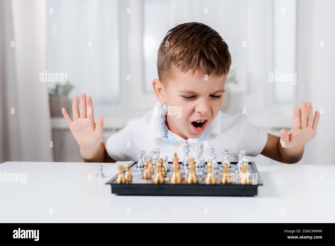 Fröhliches Kind mit Freude spielt Schach zu Hause Stockfoto