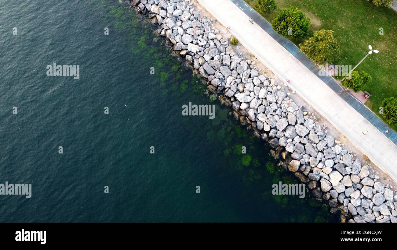 Drohnenansicht eines Küstendamms in Istanbul am Marmarameer. Küste mit Steinen Felsen und Park. Blaugrünes Meerwasser Stockfoto