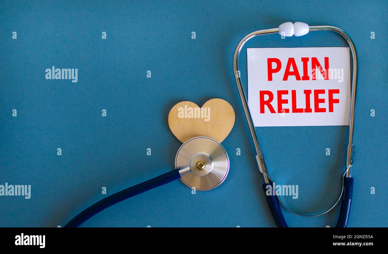 Symbol für Schmerzlinderung. Weiße Karte mit Worten Schmerzlinderung, schöner blauer Hintergrund, Holzherz und Stethoskop. Medizin und Schmerzlinderung Konzept. Stockfoto