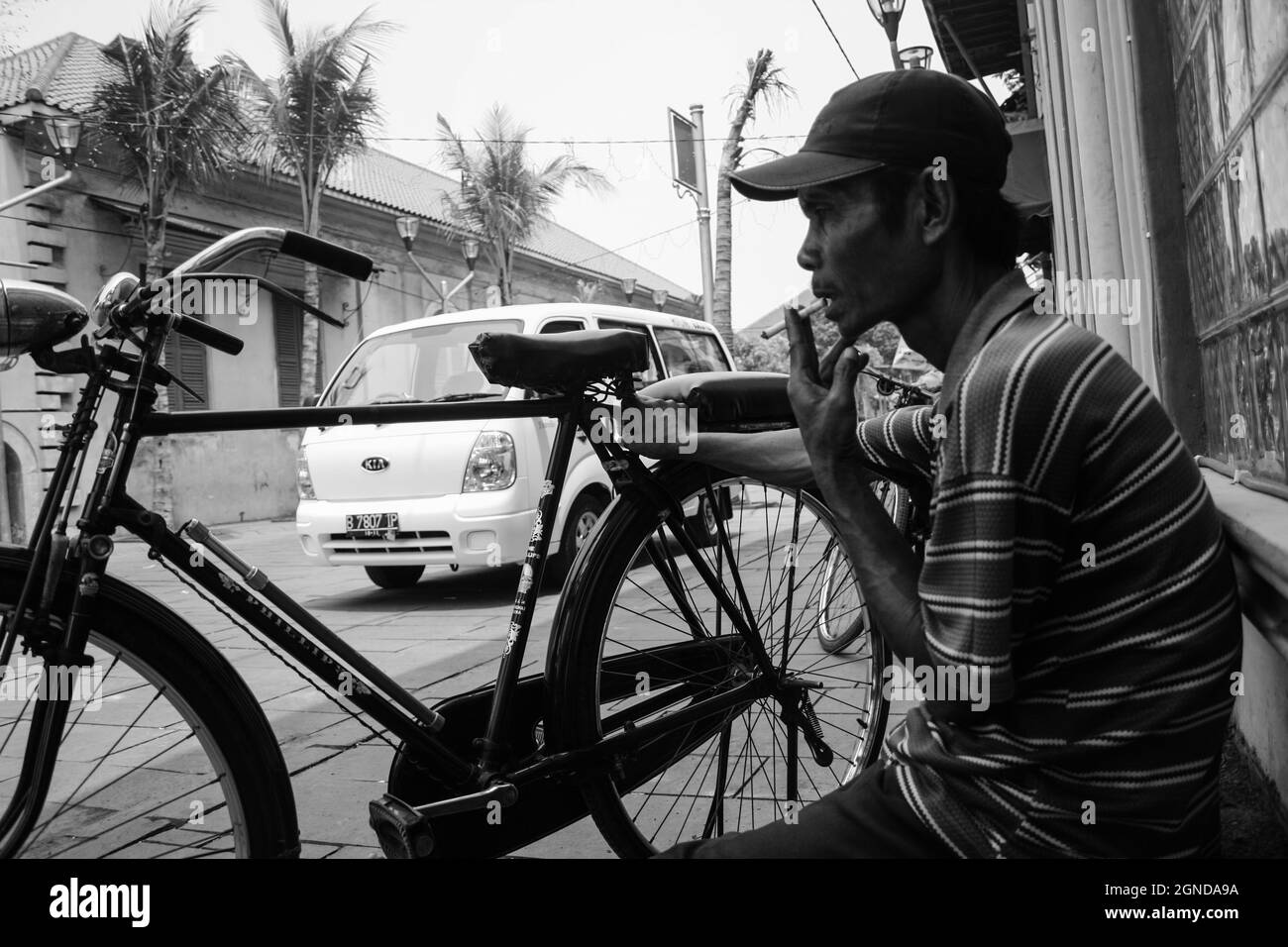 Schwarz-Weiß-Foto eines Fahrradtaxi-Fahrers, der eine Pause einnahm. In der Kota Lama Gegend, Jakarta, gibt es mehrere Radfahrer, die Touristen mitnehmen können. Stockfoto