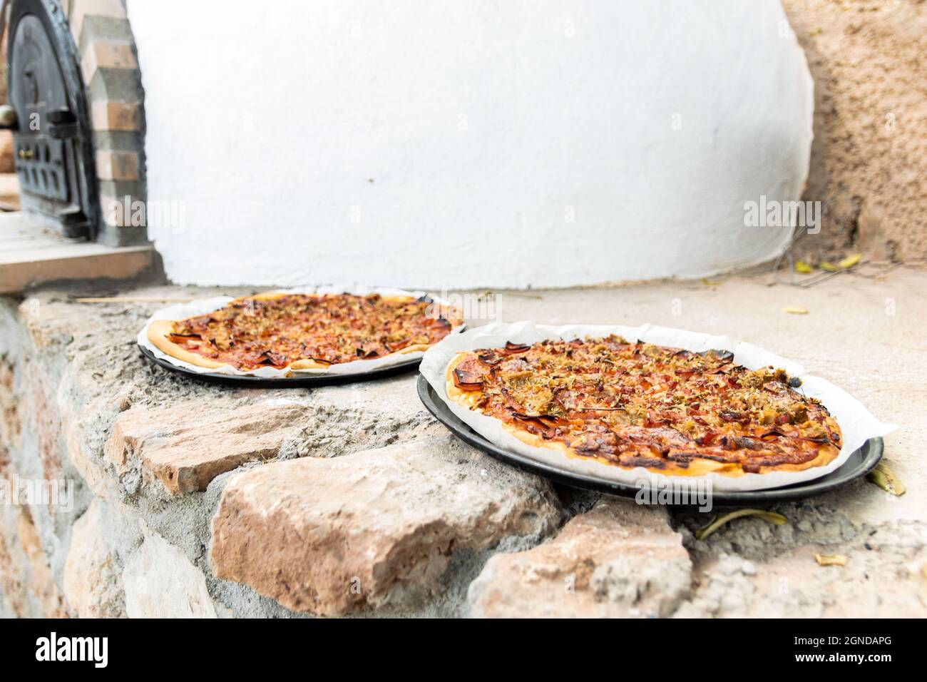 Pizza aus einem weiß lackierten, handgefertigten Holzofen, der auf der Außenseite gebaut wurde Stockfoto