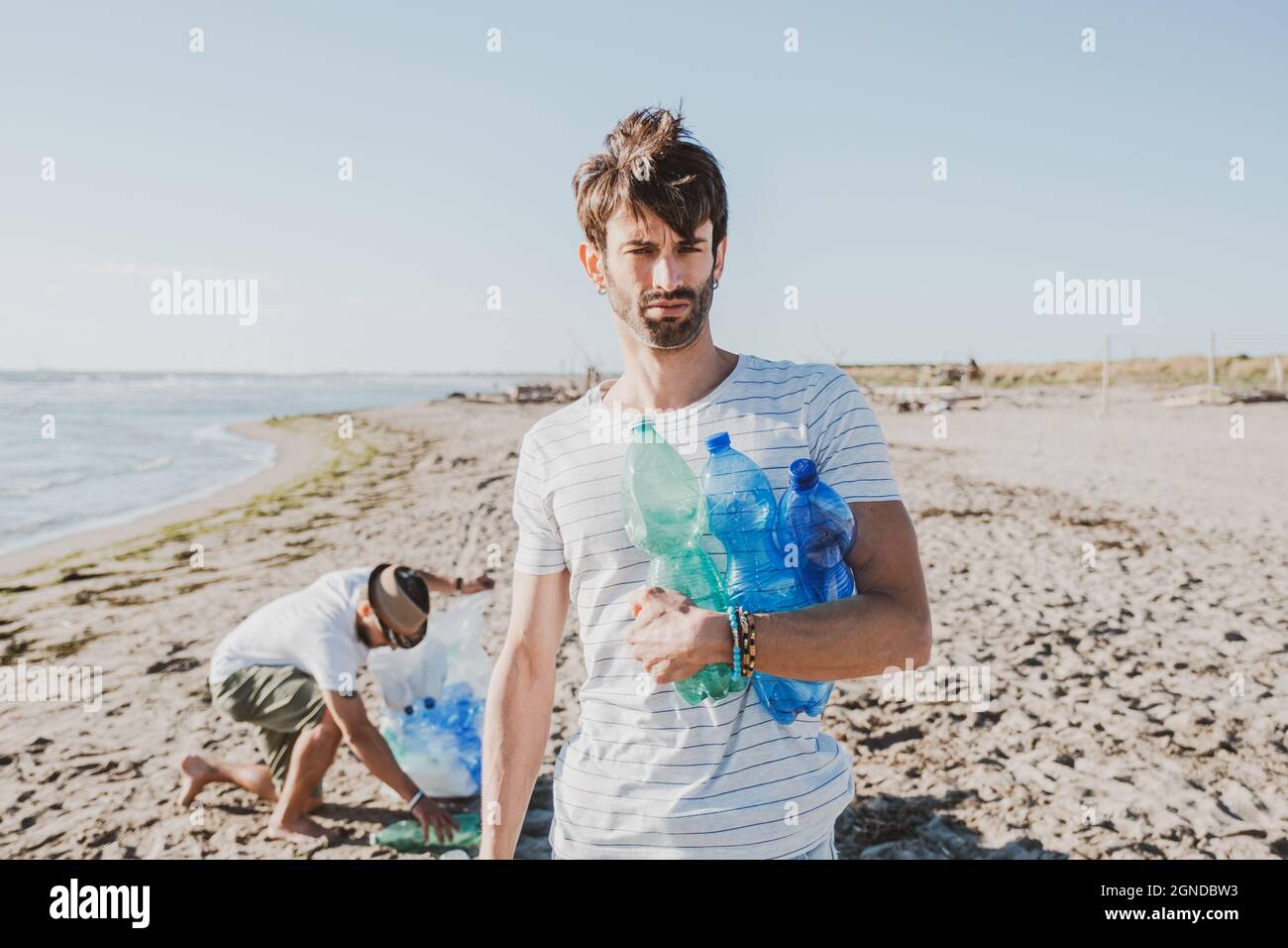 Eine Gruppe aktivistischer Freunde sammelt Plastikmüll am Strand. Leute putzen den Strand, mit Taschen. Konzept des Umweltschutzes und des Ozeans Stockfoto