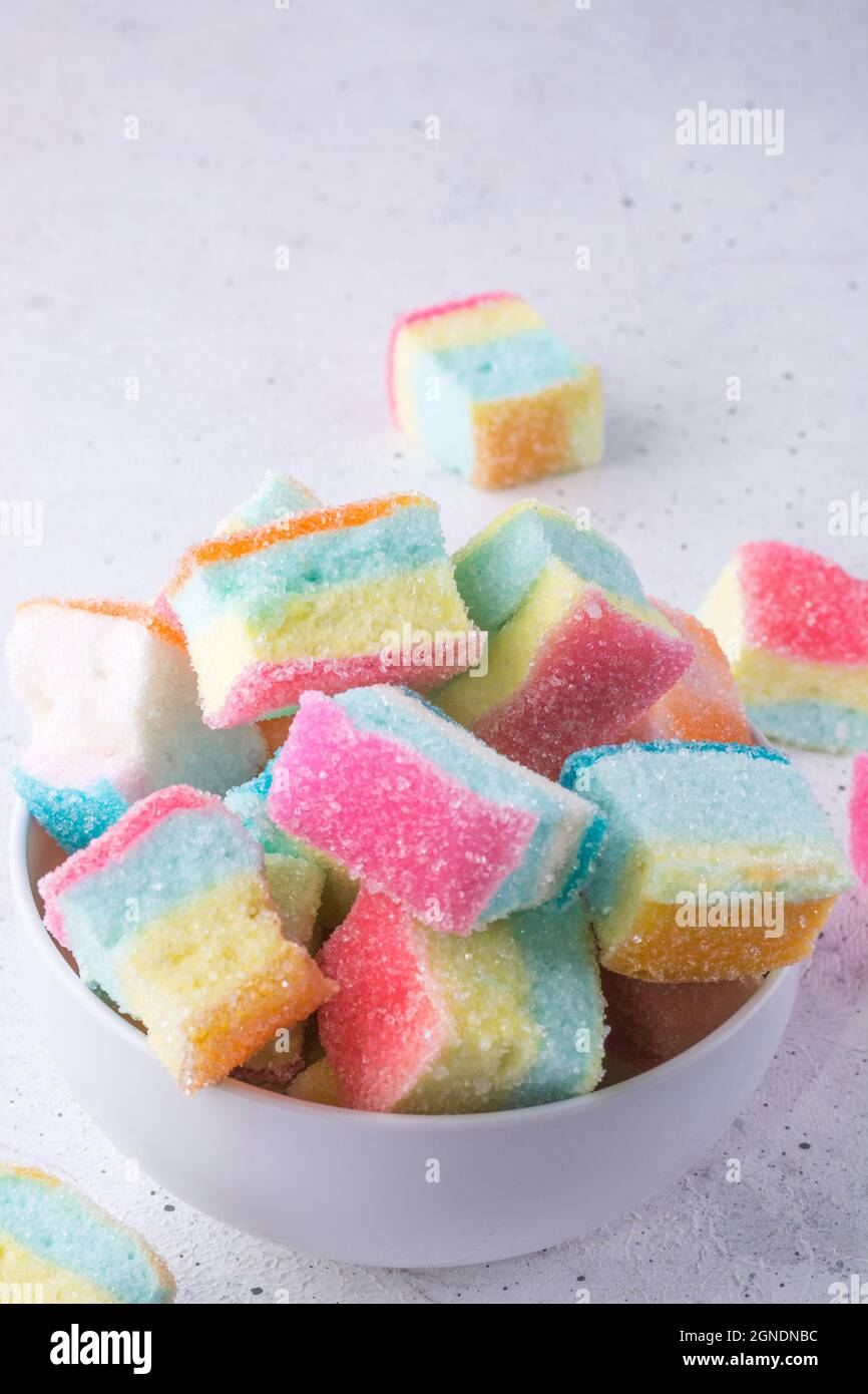 Marshallows, farbenfrohe, weiche Zuckerzuckerküche in einer Schüssel, Nahaufnahme von würfelförmigen Süßigkeiten, die auf einem weißen Hintergrund verstreut sind Stockfoto