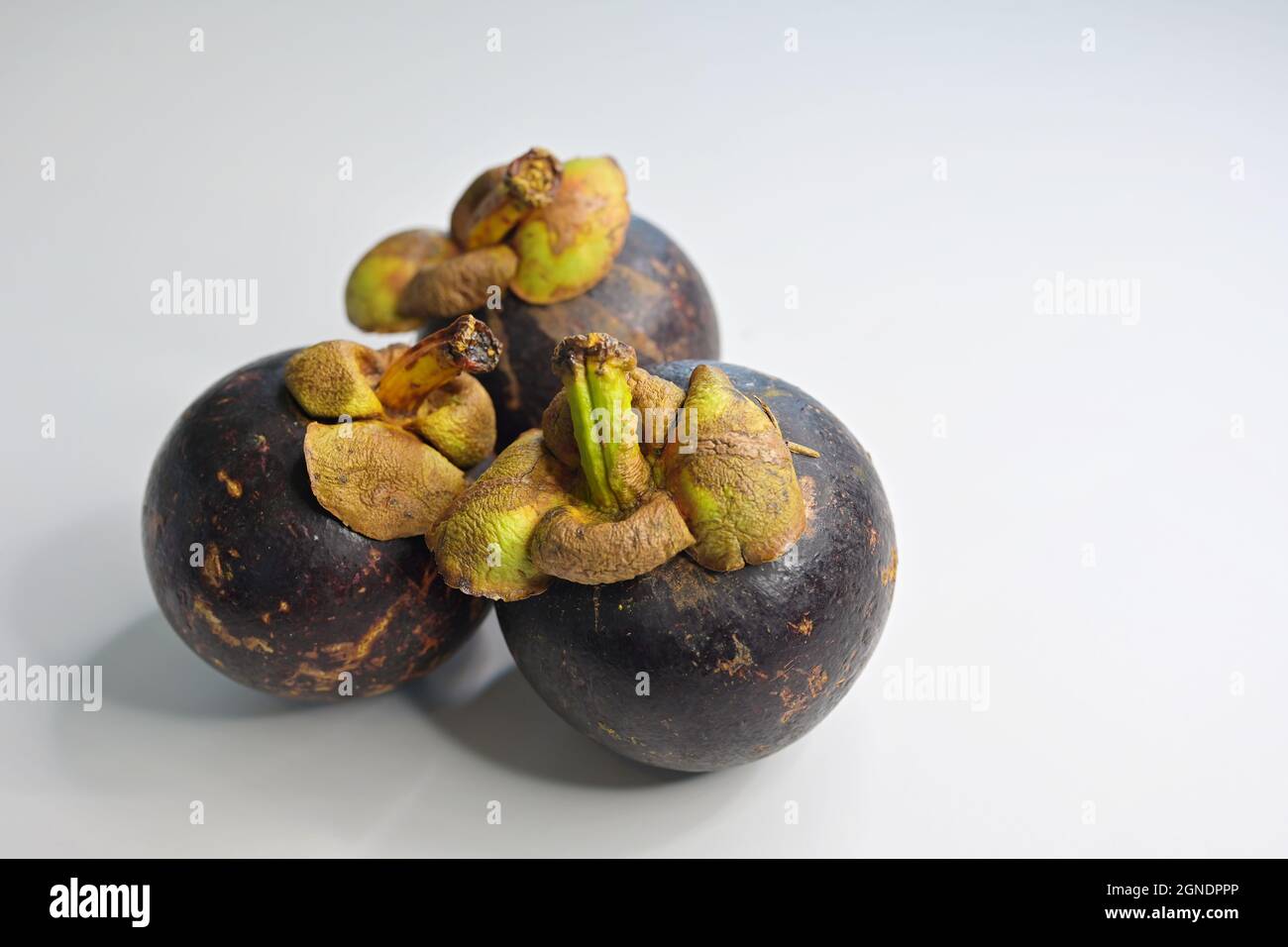 Drei ganze reife Mangostan-Früchte auf weißem Hintergrund Stockfoto