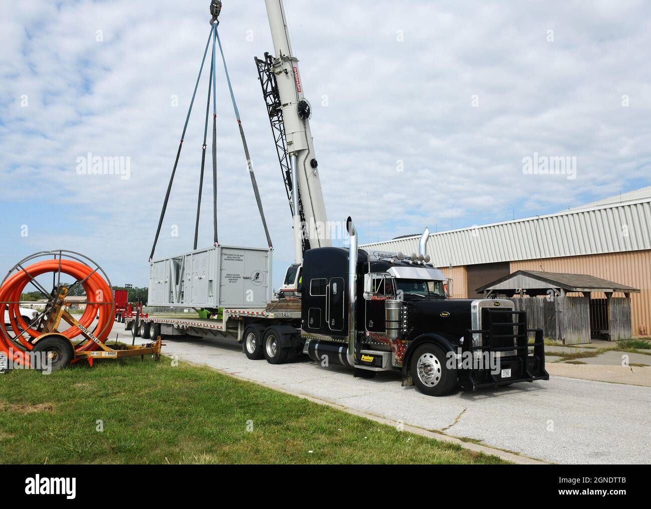 Zwei Seabees von Naval Facilities Engineering und Expeditionary Warfare Center Mobile Utilities Support Equipment Division beobachten, wie eine abgetrennte 2500 kVA-Unterstation an einem Kran hängt, nachdem sie die 595. Command and Control Allman Maintenance Facility der Offutt Air Force, Nebraska, vorübergehend mit Strom versorgt haben. (USA Luftwaffe Foto von Charles J. Haymond) Stockfoto