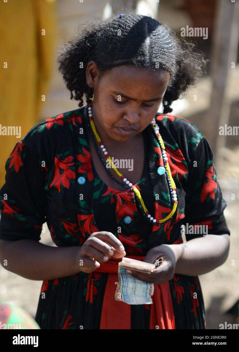 Eine Oromo-Frau zählt ihr Geld auf dem Wochenmarkt in Bati, Äthiopien. Stockfoto