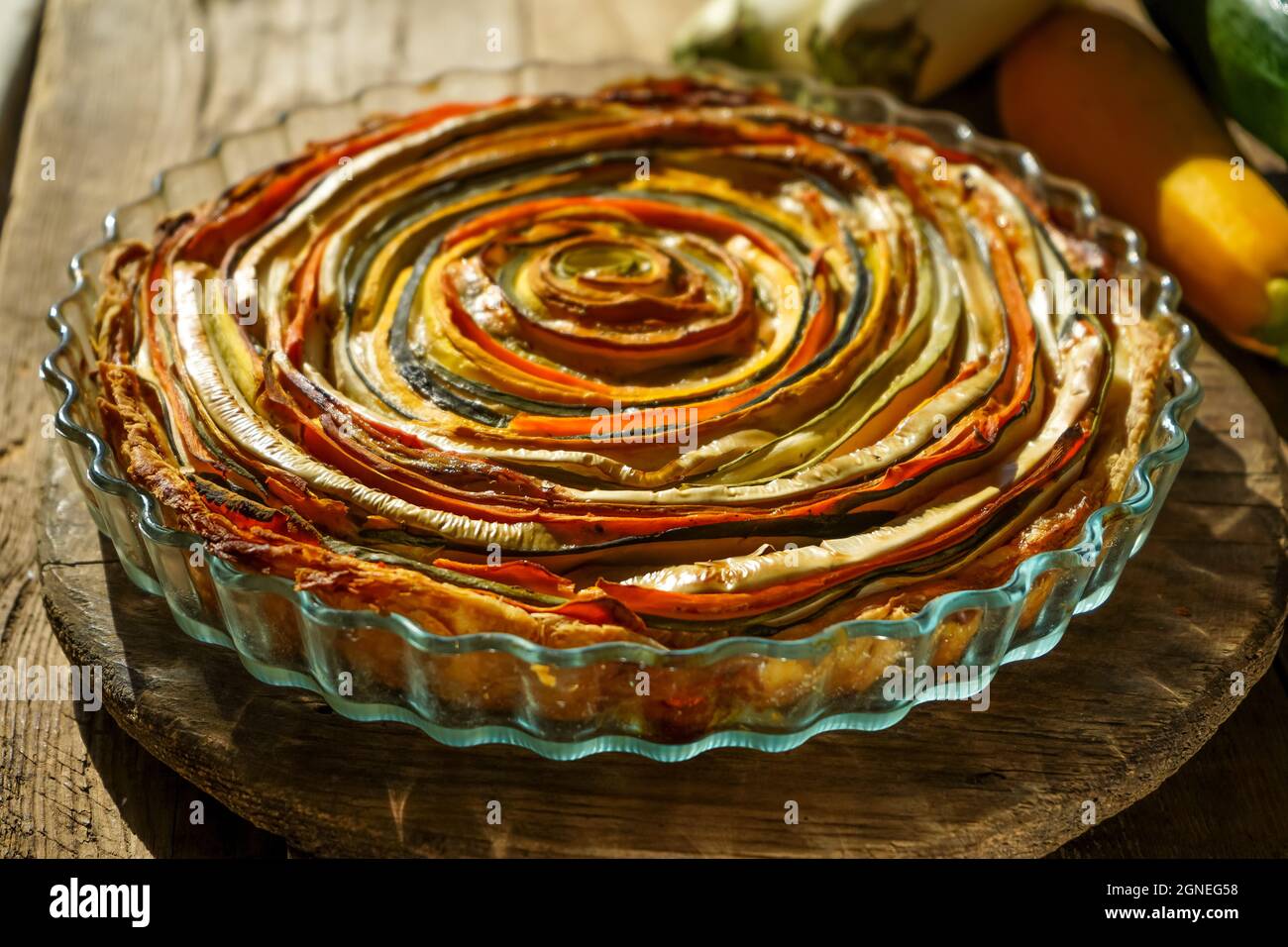 Gemüsekuchen mexikanische Sonne. Runde, offene Torte aus Zucchini, Auberginen und Karotten. Nahaufnahme von oben. Gesunde pflanzliche Lebensmittel. Vegetarismus. Spirale Stockfoto