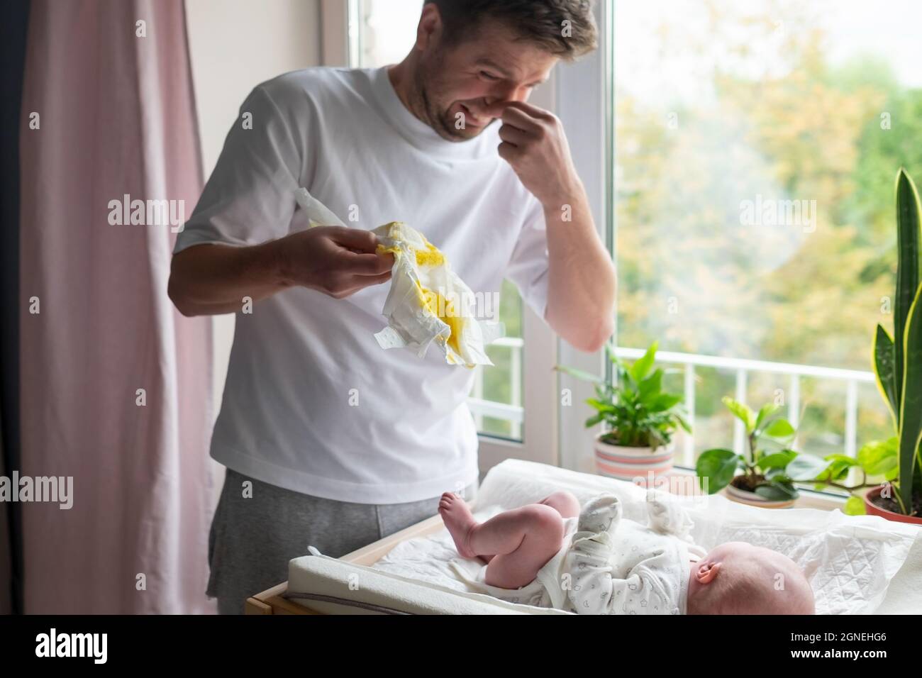 Kaukasischer Vater, der sich um seine neugeborene Tochter oder seinen Sohn kümmert, der die Windel wechselt Stockfoto