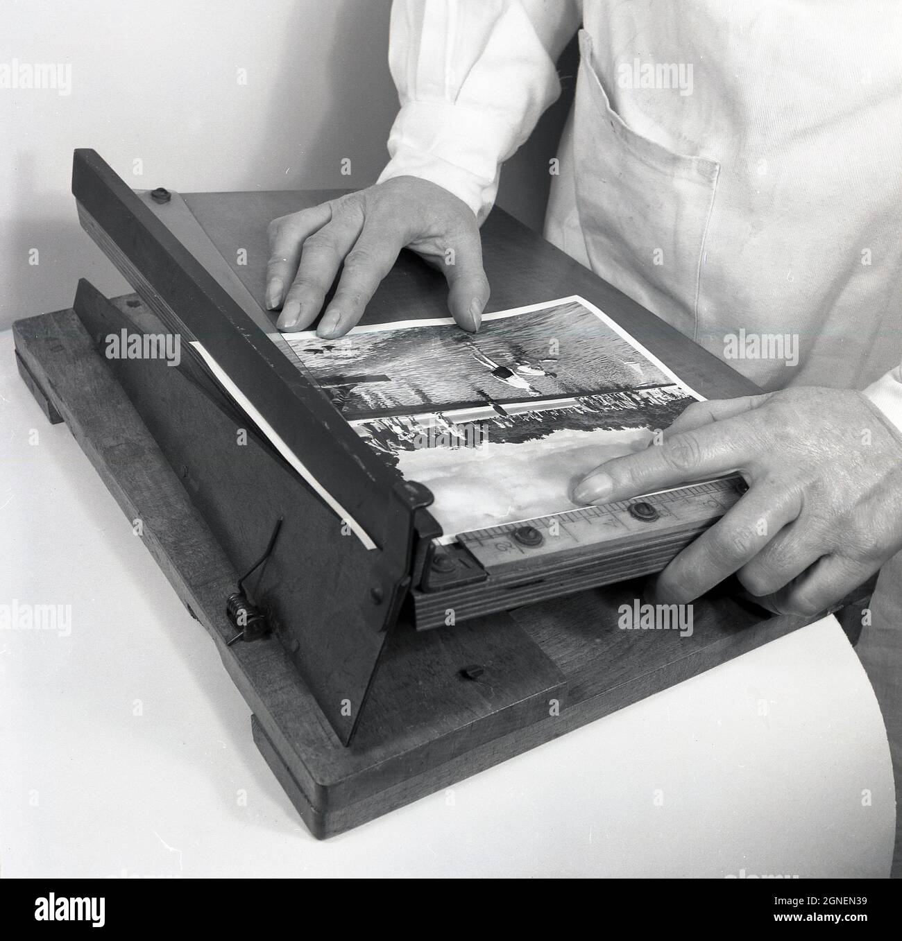 1950er Jahre, historisch, mit einem hölzernen Fotoschneider, um einen Schwarz-Weiß-Druck zu schneiden, der von einem Kamerafilm-Negativ, England, Großbritannien, produziert wurde. Stockfoto