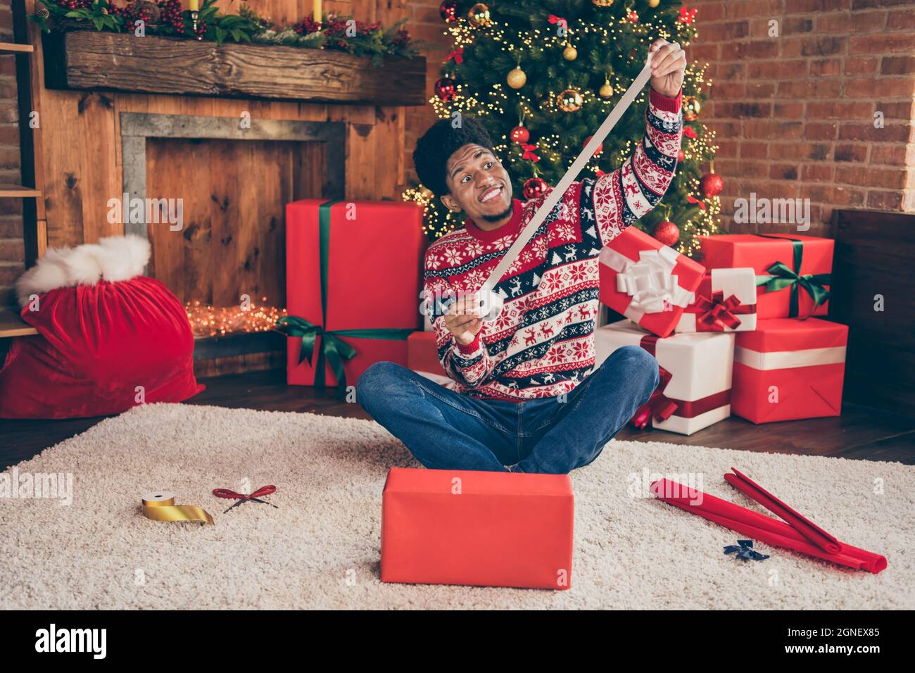 In voller Länge Körpergröße Foto Mann halten Band Dekoration xmas Geschenk in der Nähe immergrünen weihnachtsbaum Stockfoto