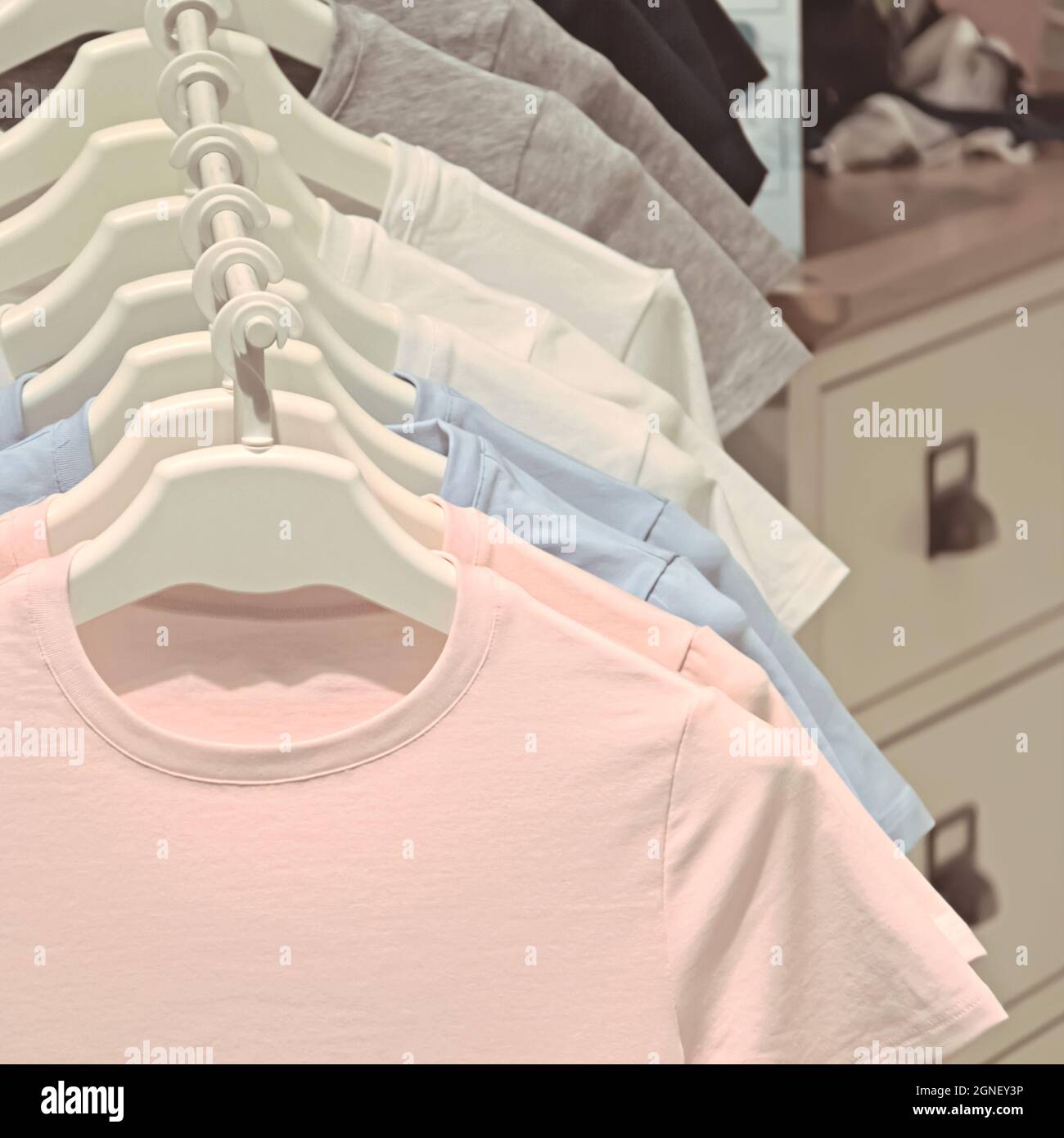 Helle T-Shirts hängen in einer Reihe an einem Kleiderbügel, Damenbekleidung aus Baumwolle Stockfoto
