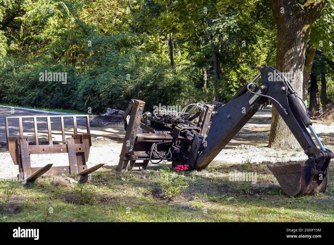 Anbaugeräte an einem kleinen Traktor. Laden von Gabeln. Eimer von kleinen Baggern. Starke Zähne sind bereit, in den Boden zu beißen. Stockfoto