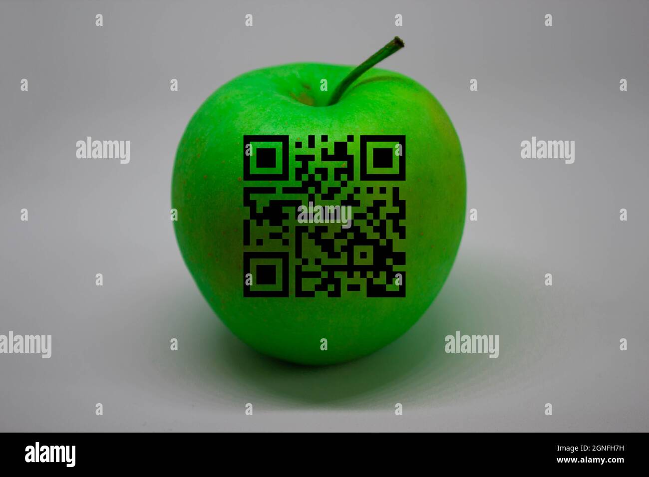 Ein grüner Apfel mit QR-Code darauf. Weißer Hintergrund. Textbereich. Stockfoto