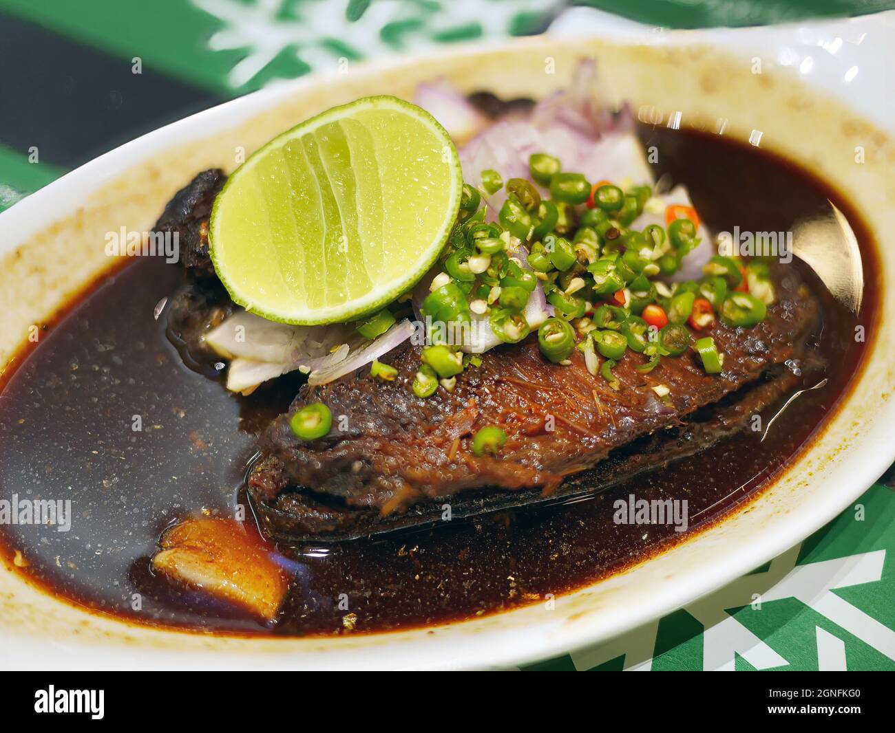 Süßer und salziger frischer Makreleneintopf mit gehackter, gehackter roter Zwiebel und in Scheiben geschnittener Zitrone auffüllen Stockfoto